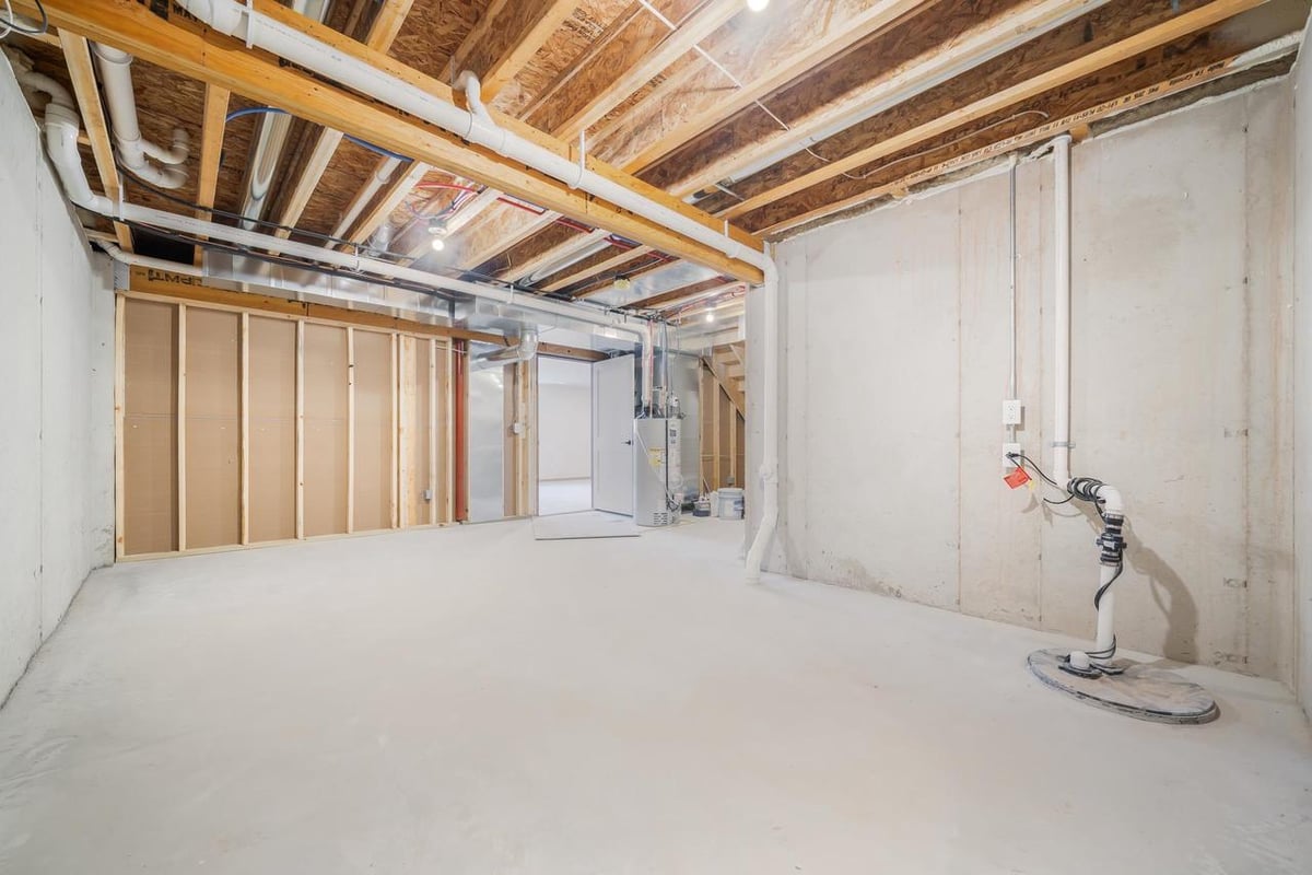 Unfinished basement with exposed beams, concrete floors, and utility hookups in a Fox Cities home