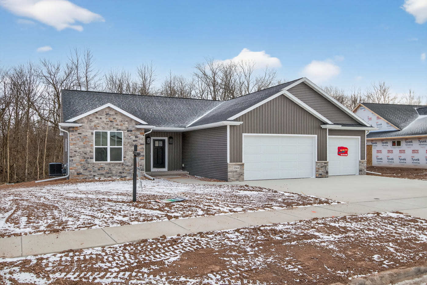 Front exterior of a newly built home with stone and vertical siding in the Fox Cities, featuring a 3-car garage