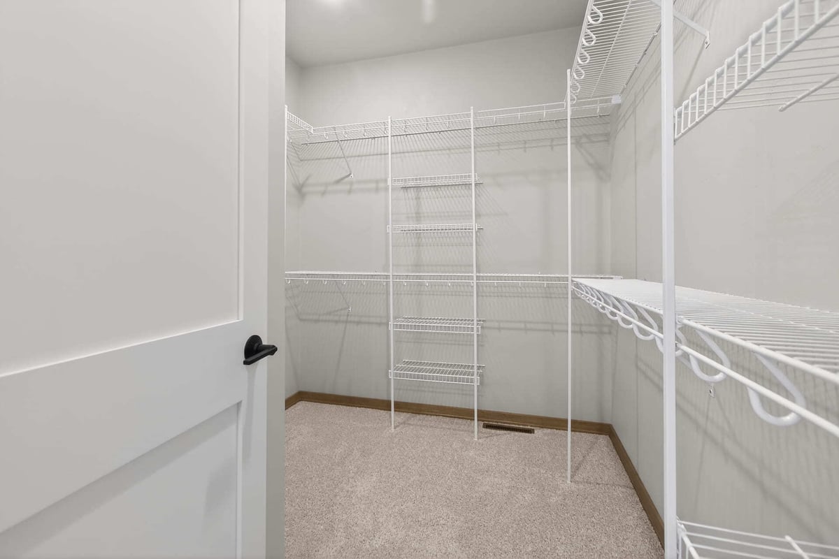 Spacious walk-in closet with white wire shelving and neutral carpet in a Fox Cities home