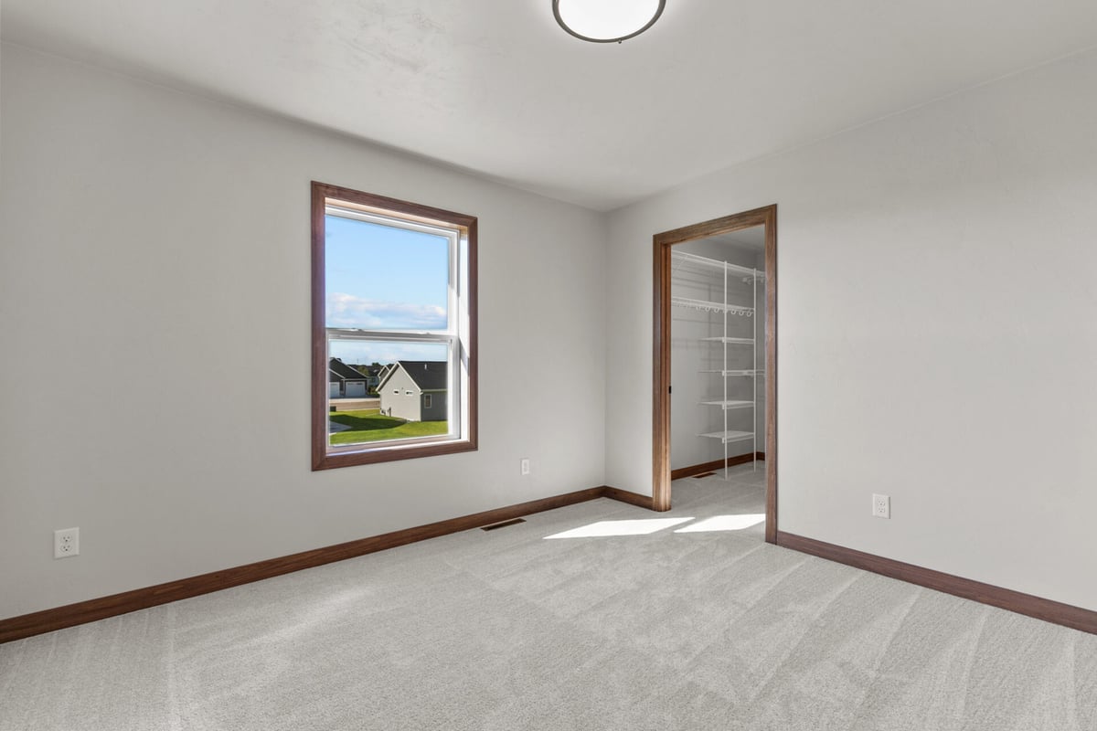 Bright carpeted bedroom with window and walk-in closet by Midwest Design Homes in Neenah, WI