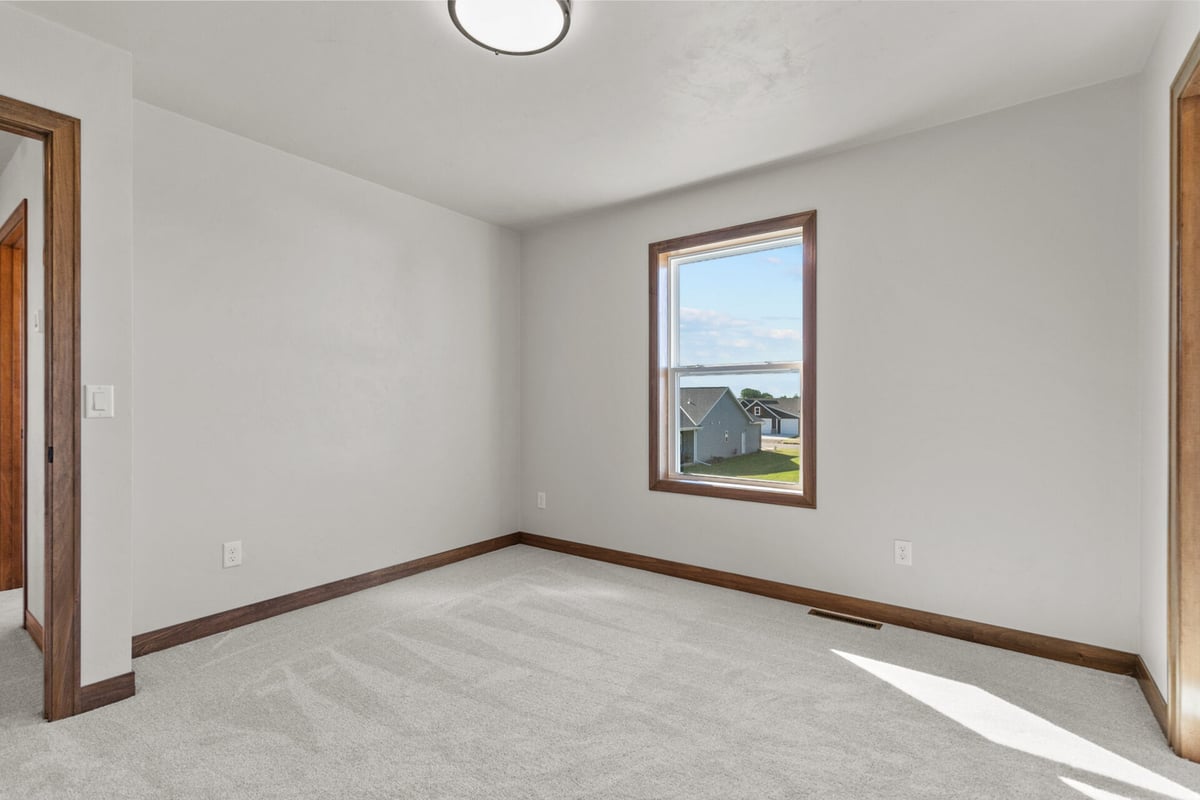 Carpeted bedroom with single window and simple layout in a Midwest Design Homes project in Bellevue, WI