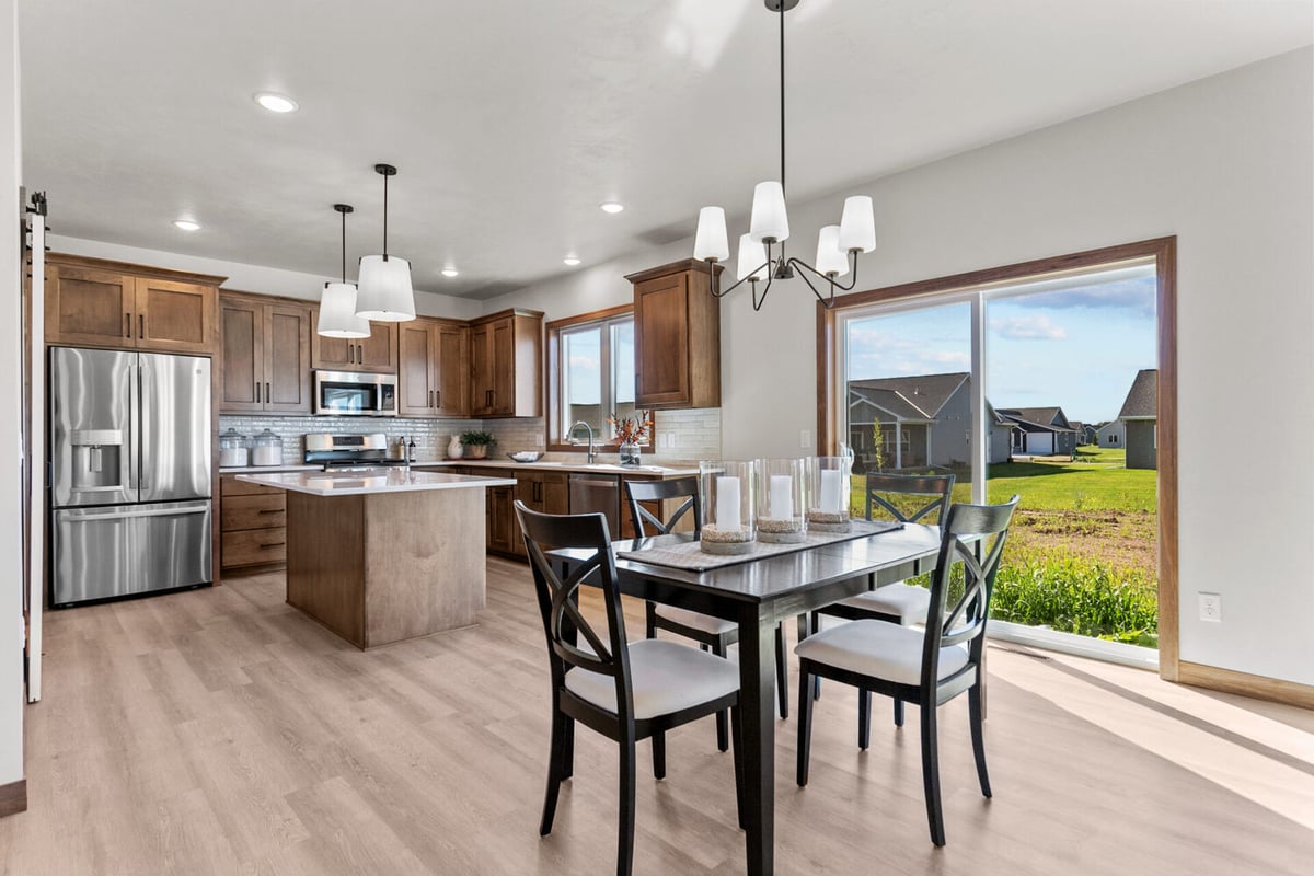 Dining and kitchen space with pendant lights and black chairs in custom home by Midwest Design Homes in Kaukauna, WI