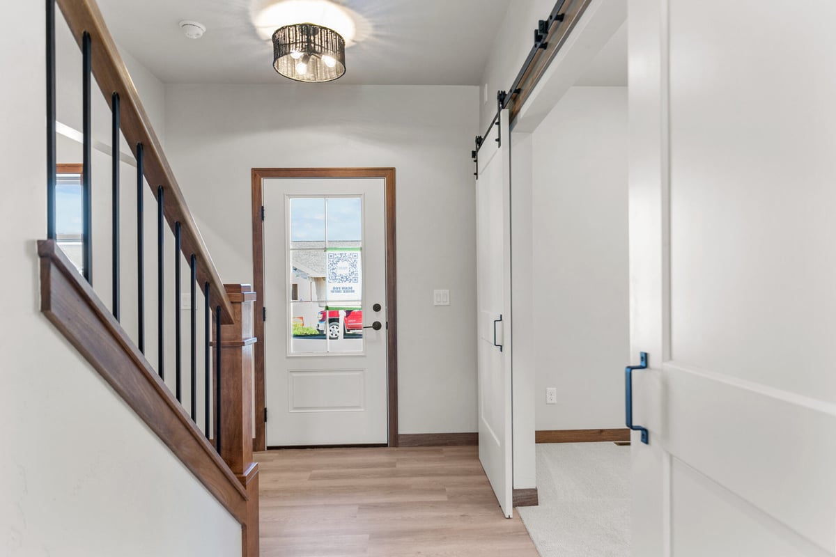 Entryway with glass-paneled door and barn door access in a custom Kaukauna, WI home by Midwest Design Homes