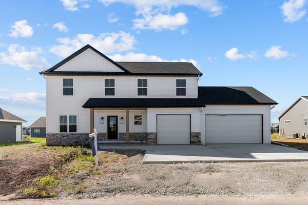 Front view of white two-story custom home with black roof and finished driveway in Kaukauna, WI by Midwest Design Homes