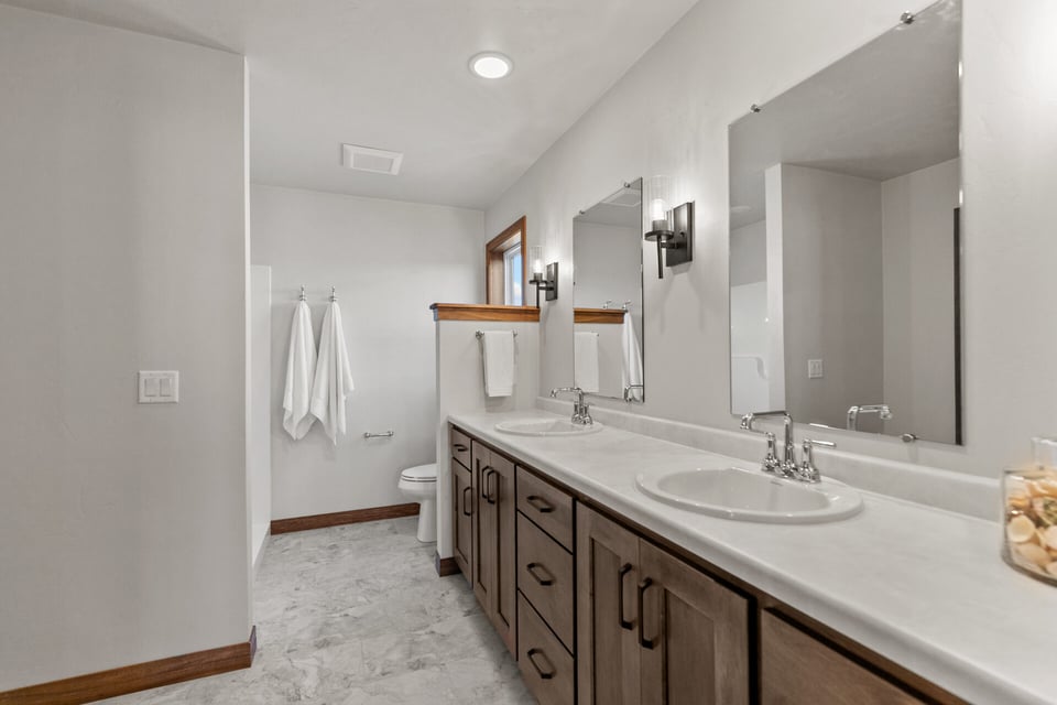 Master bathroom with dual sinks and wood cabinetry in a custom Green Bay, WI home by Midwest Design Homes
