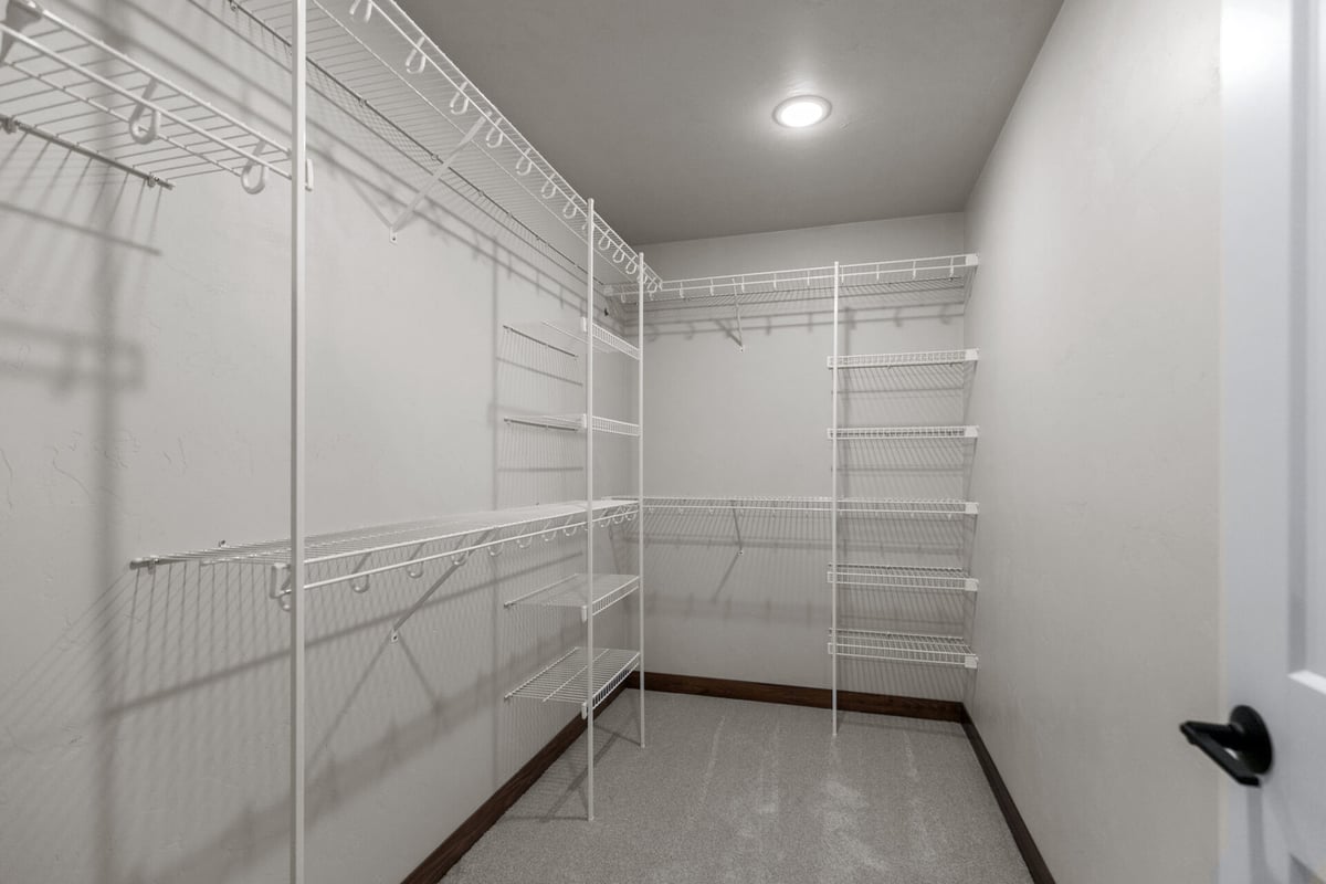 Master closet with ample storage and white shelving system by Midwest Design Homes in Harrison, WI