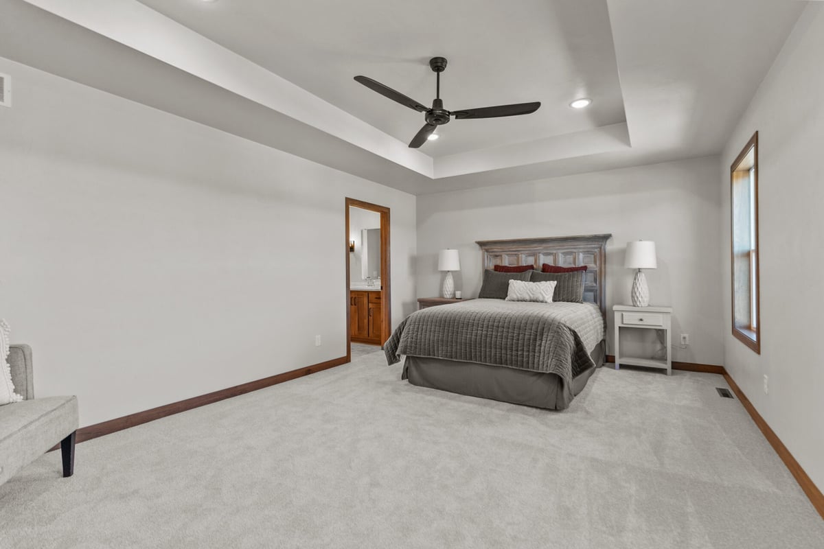 Spacious master bedroom with tray ceiling and ceiling fan in a Green Bay, WI home by Midwest Design Homes