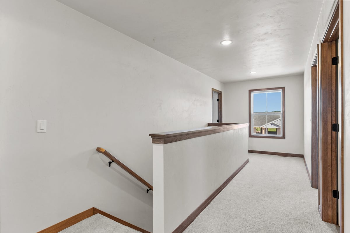 Upper hallway with carpeted flooring and wood trim in a Green Bay, WI custom home by Midwest Design Homes