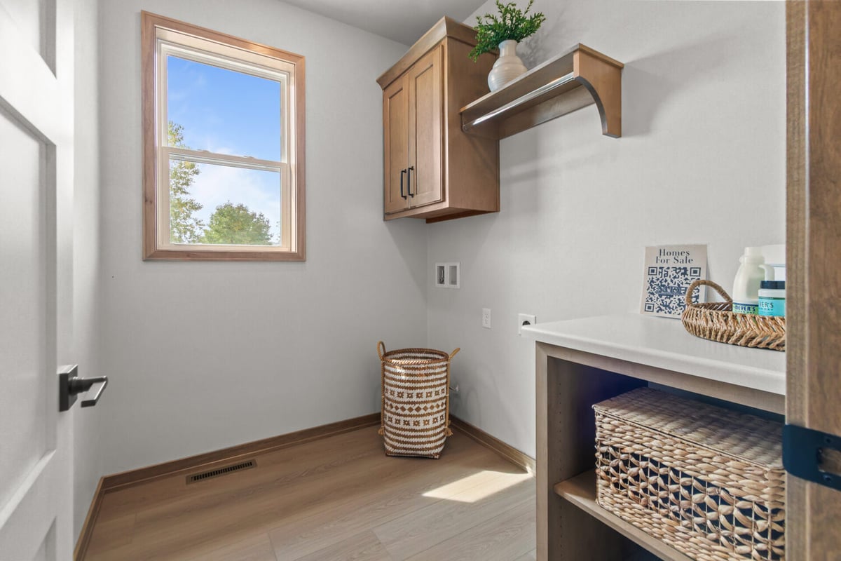 Bright laundry room with wood cabinetry in custom home by Midwest Design Homes in Harrison, WI
