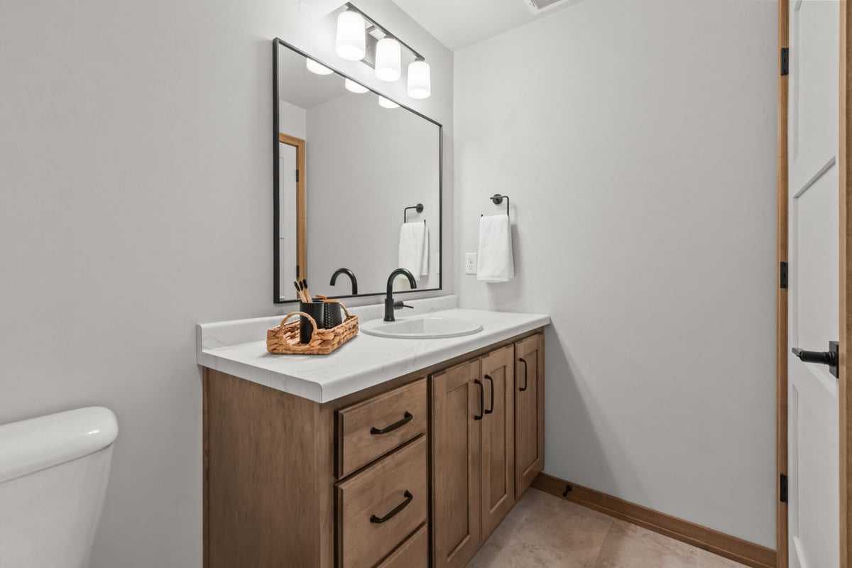 Custom bathroom vanity with wood cabinetry and large framed mirror by Midwest Design Homes in De Pere, WI