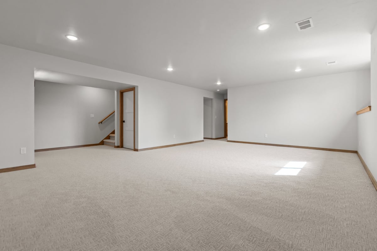 Finished basement space with stairs and hallway access in Lawrence, WI by Midwest Design Homes