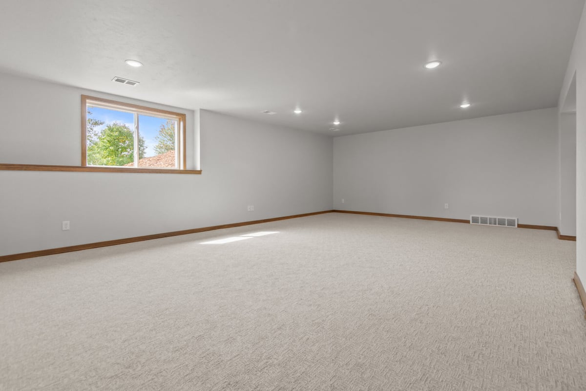 Large finished basement living area with soft carpet and recessed lighting in Bellevue, WI by Midwest Design Homes