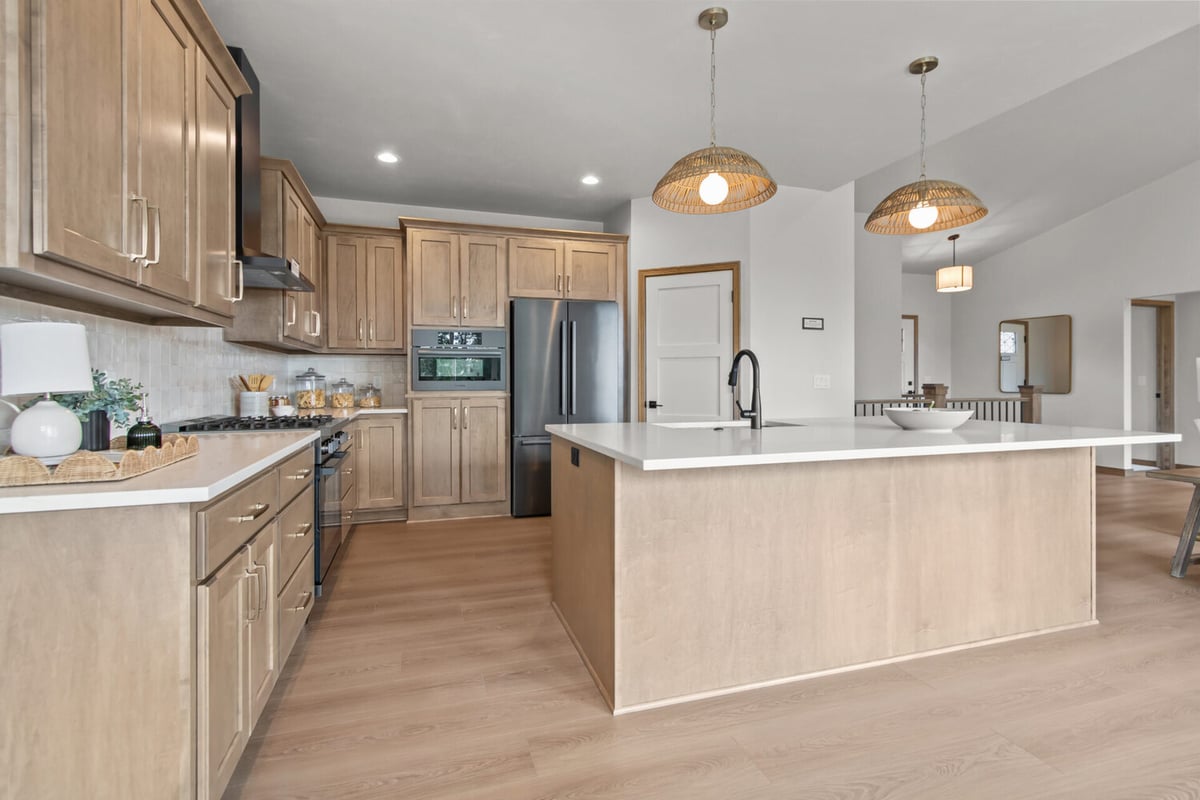Open-concept kitchen with natural wood cabinetry and large island in a custom home by Midwest Design Homes in Kaukauna, WI