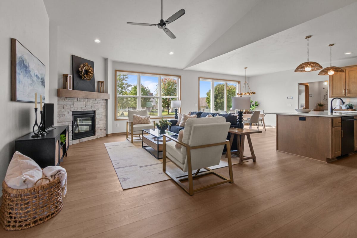 Open-concept living area with stone fireplace and patio views by Midwest Design Homes in Ellington, WI