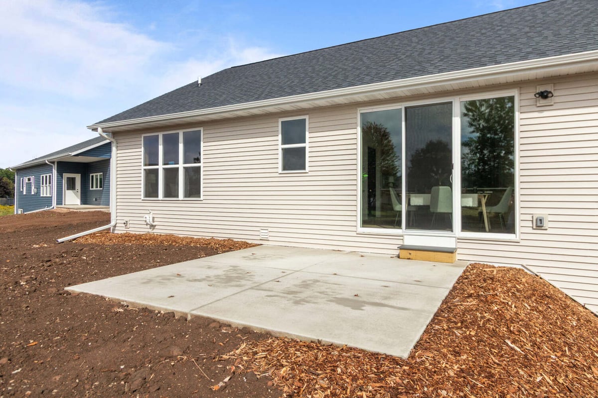 Rear exterior with concrete patio and sliding glass doors in a custom home by Midwest Design Homes in Greenville, WI