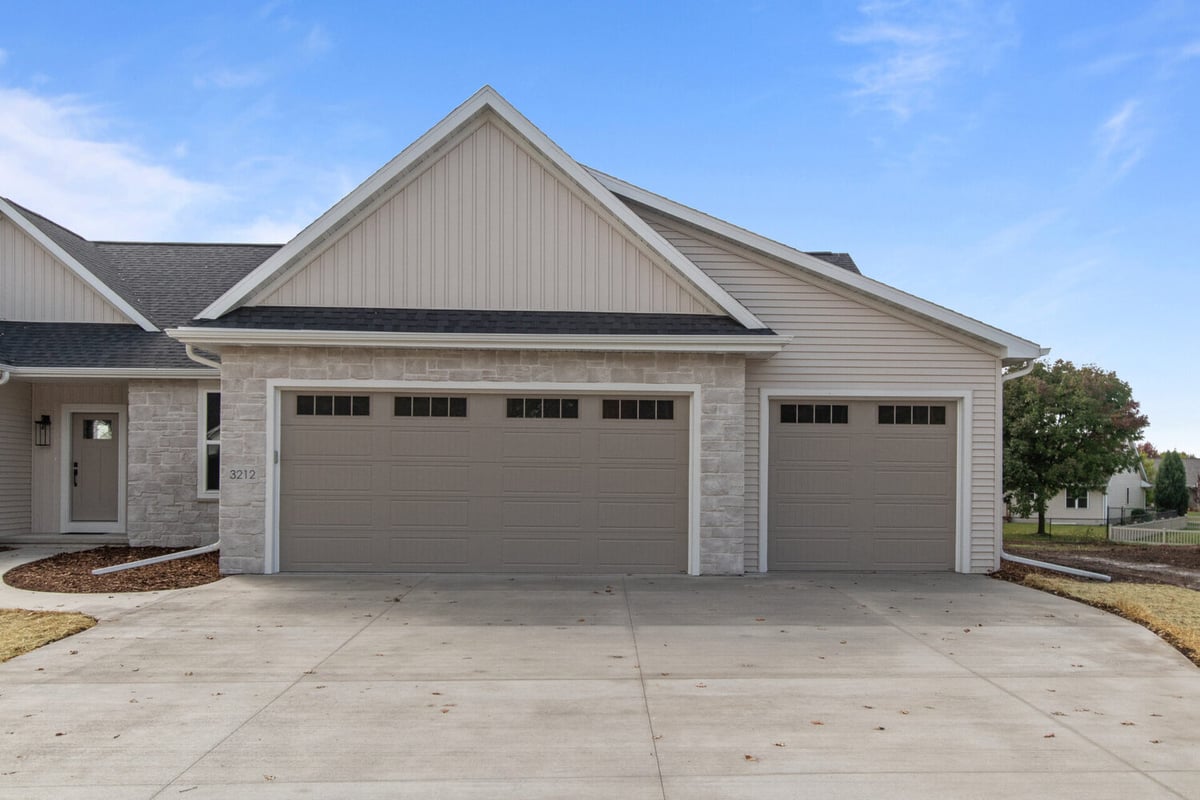 Three-car garage exterior with stone and siding finishes in a custom home by Midwest Design Homes in Kaukauna, WI