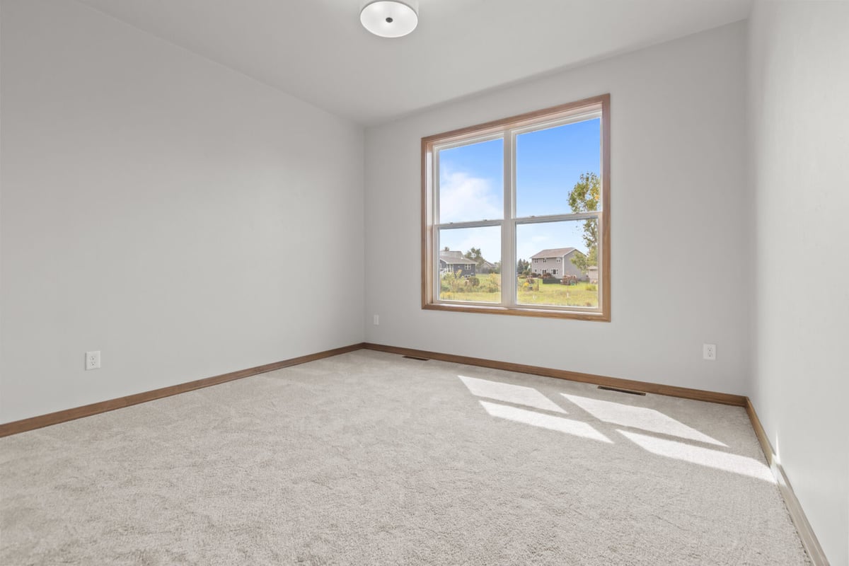 Unfurnished carpeted bedroom with bright window in Harrison, WI custom home by Midwest Design Homes