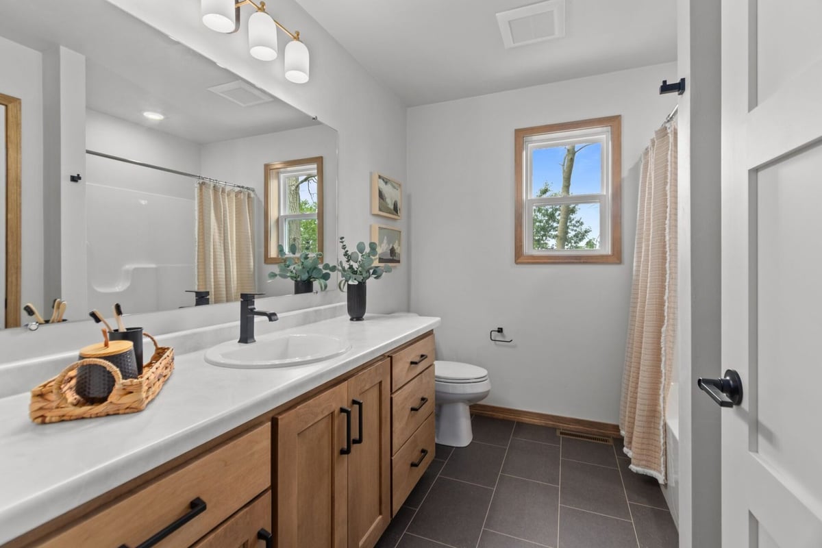 Bathroom with double vanity and dark tile flooring in a Neenah, WI custom home by Midwest Design Homes