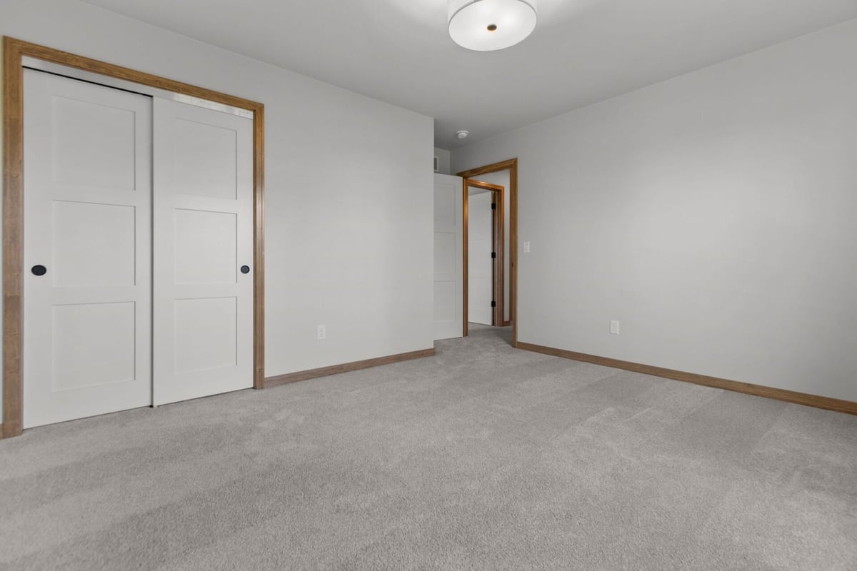 Bedroom with double-door closet and hallway access in an Appleton, WI custom home by Midwest Design Homes