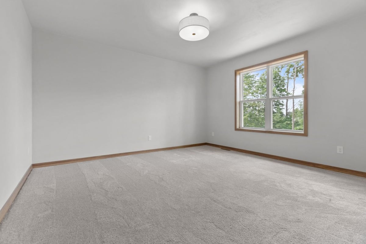 Bright bedroom with neutral carpet and large window in a custom home in Fox Cities, WI by Midwest Design Homes