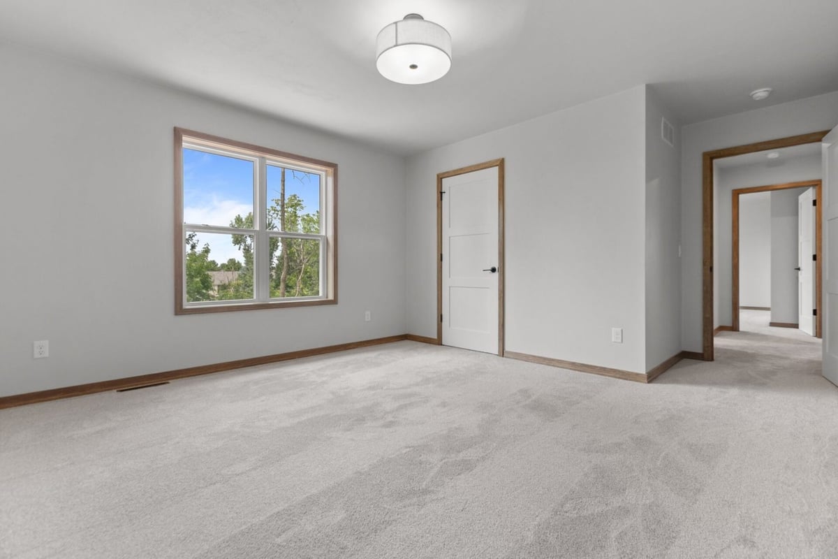 Custom bedroom with soft carpet and natural light in a Harrison, WI home by Midwest Design Homes