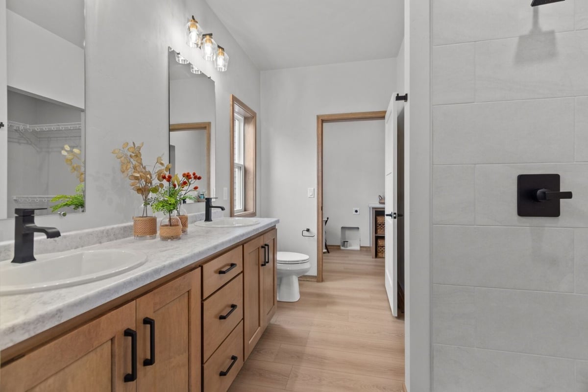 Custom double vanity bathroom with wood cabinets in an Ellington, WI home by Midwest Design Homes