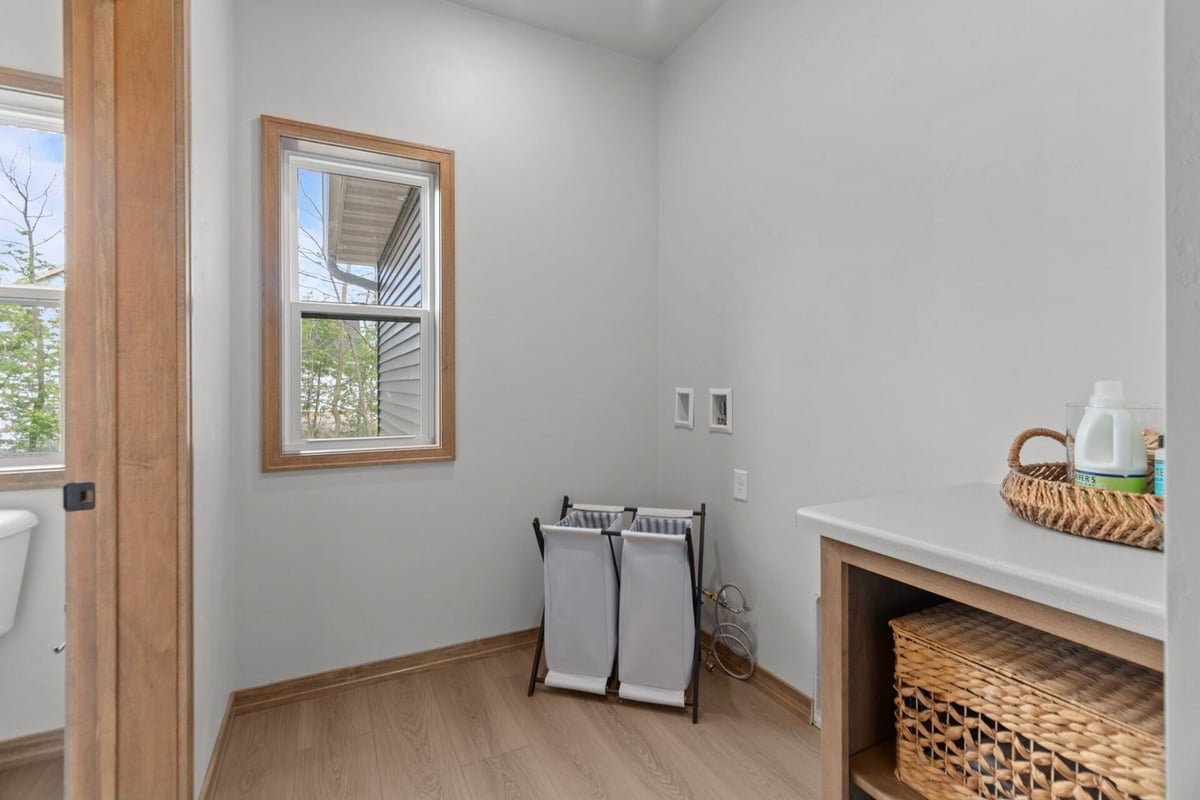 Custom laundry room with wood flooring and built-in storage in a Green Bay, WI home by Midwest Design Homes
