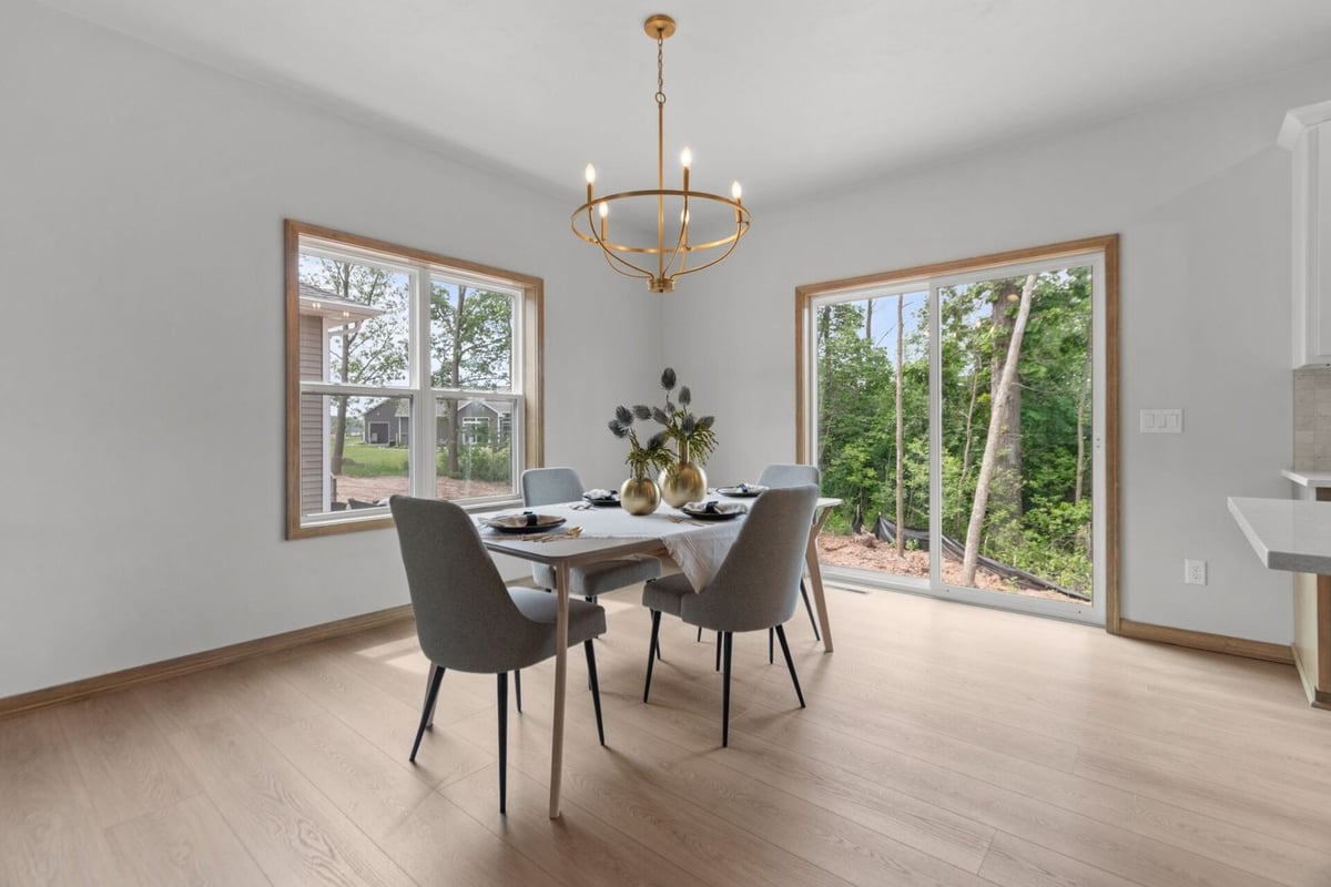 Dining room with large windows and modern chandelier in a custom home in Fox Cities, WI by Midwest Design Homes