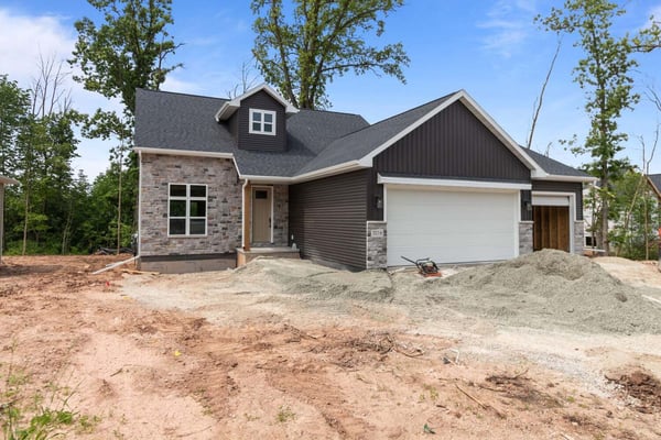Front exterior of a custom home under construction in Kaukauna, WI by Midwest Design Homes featuring stone and vertical siding