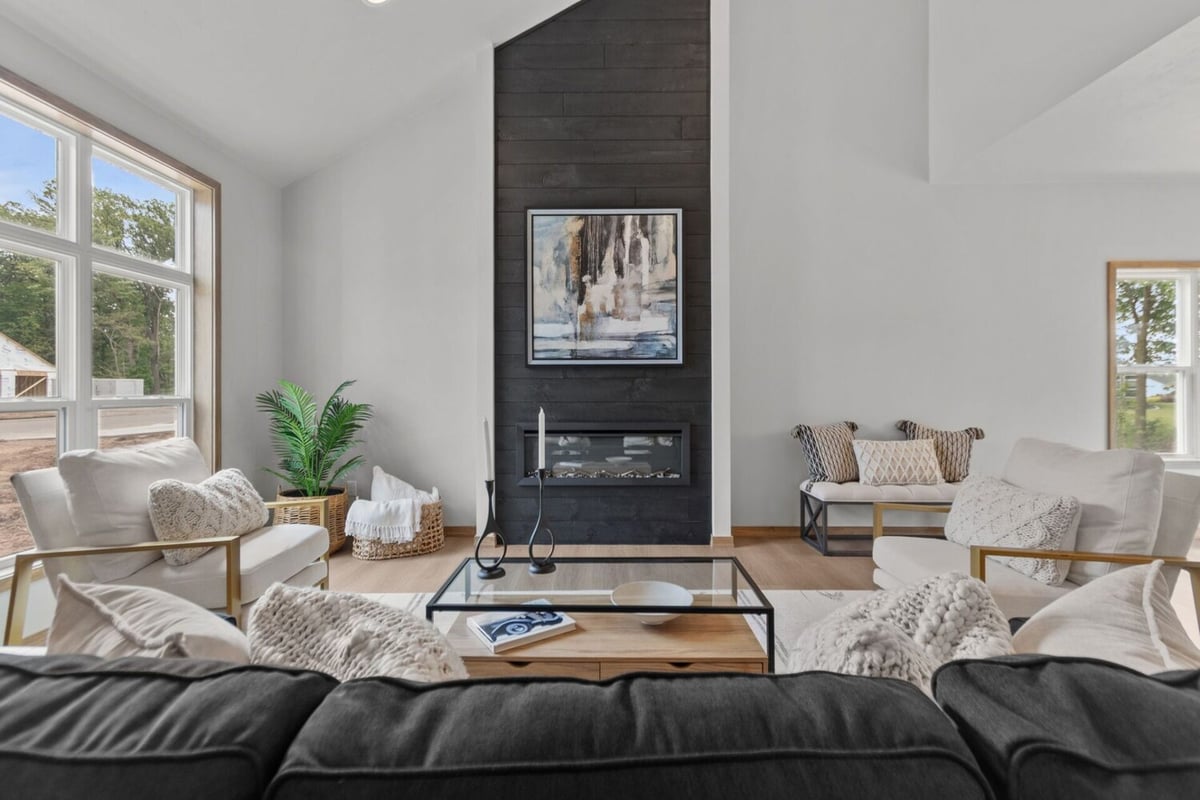 Living room with black sofa and fireplace in a custom De Pere, WI home by Midwest Design Homes