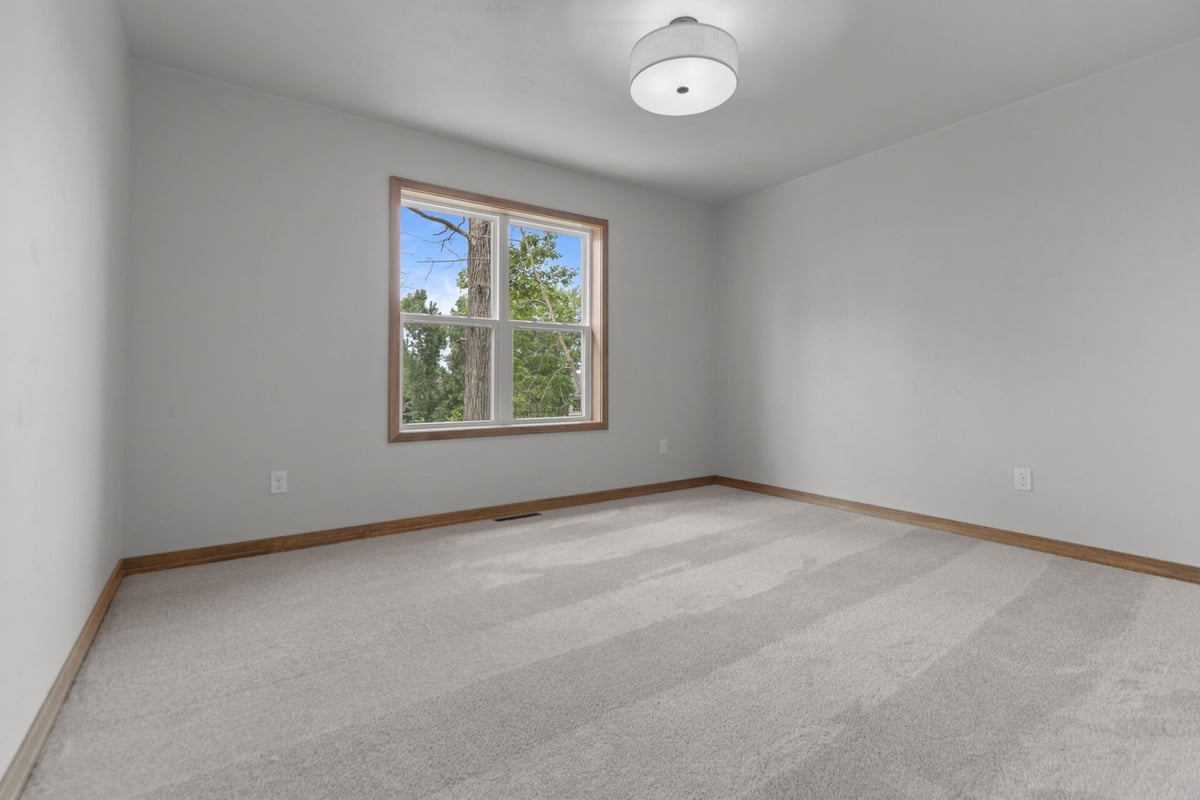 Secondary bedroom with views of backyard trees in a Bellevue, WI home