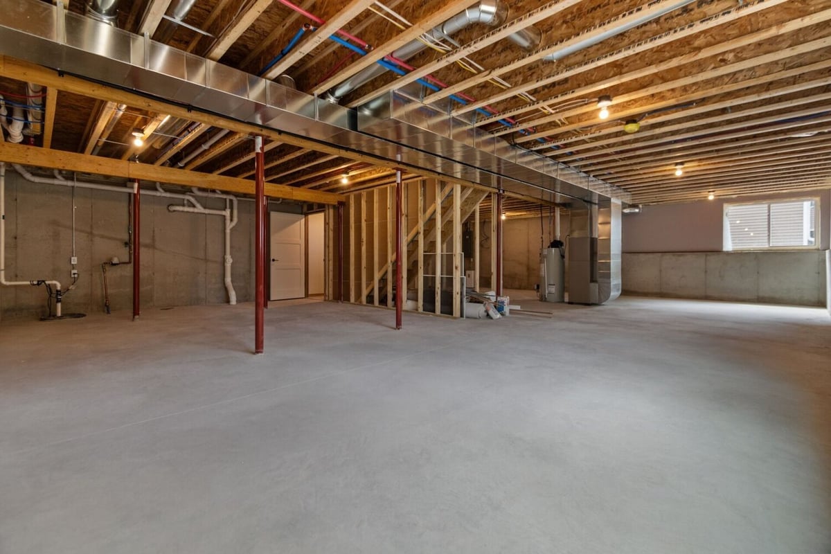 Unfinished basement of a custom home in Kaukauna, WI by Midwest Design Homes showcasing ductwork and concrete flooring