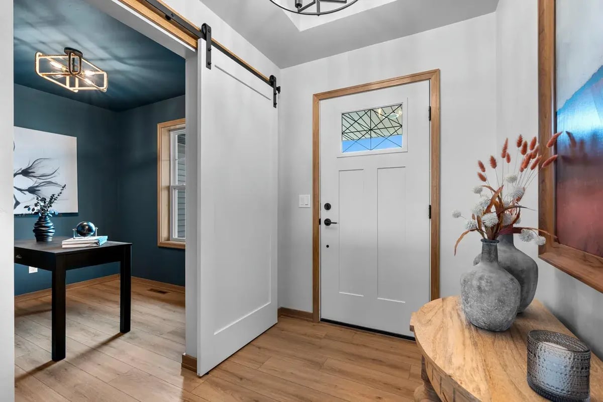 Bright Fox Cities entryway with a white front door, wood accents, and a sliding barn door leading into a stylish home office