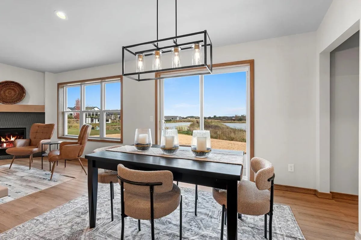 Dining area in the Fox Cities with large windows, modern light fixture, and views of a pond and surrounding neighborhood