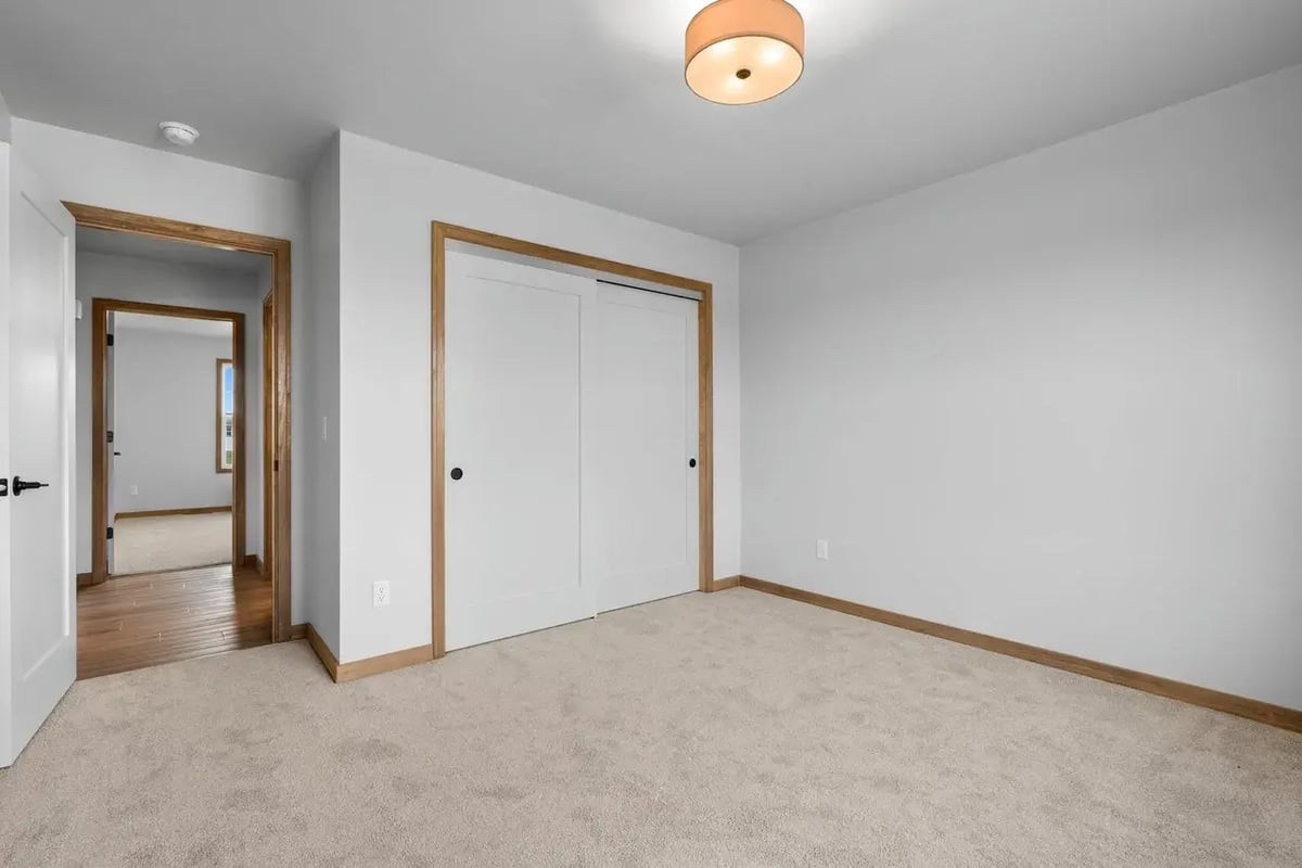 Empty bedroom with carpet and white sliding closet doors in a Fox Cities home