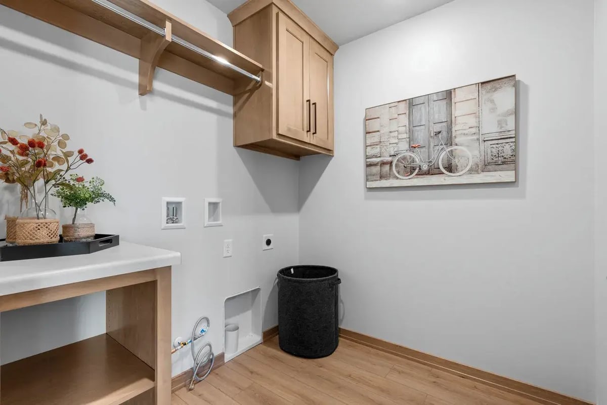 Laundry room in a Fox Cities home featuring wood cabinets, white countertops, and washer/dryer hookups