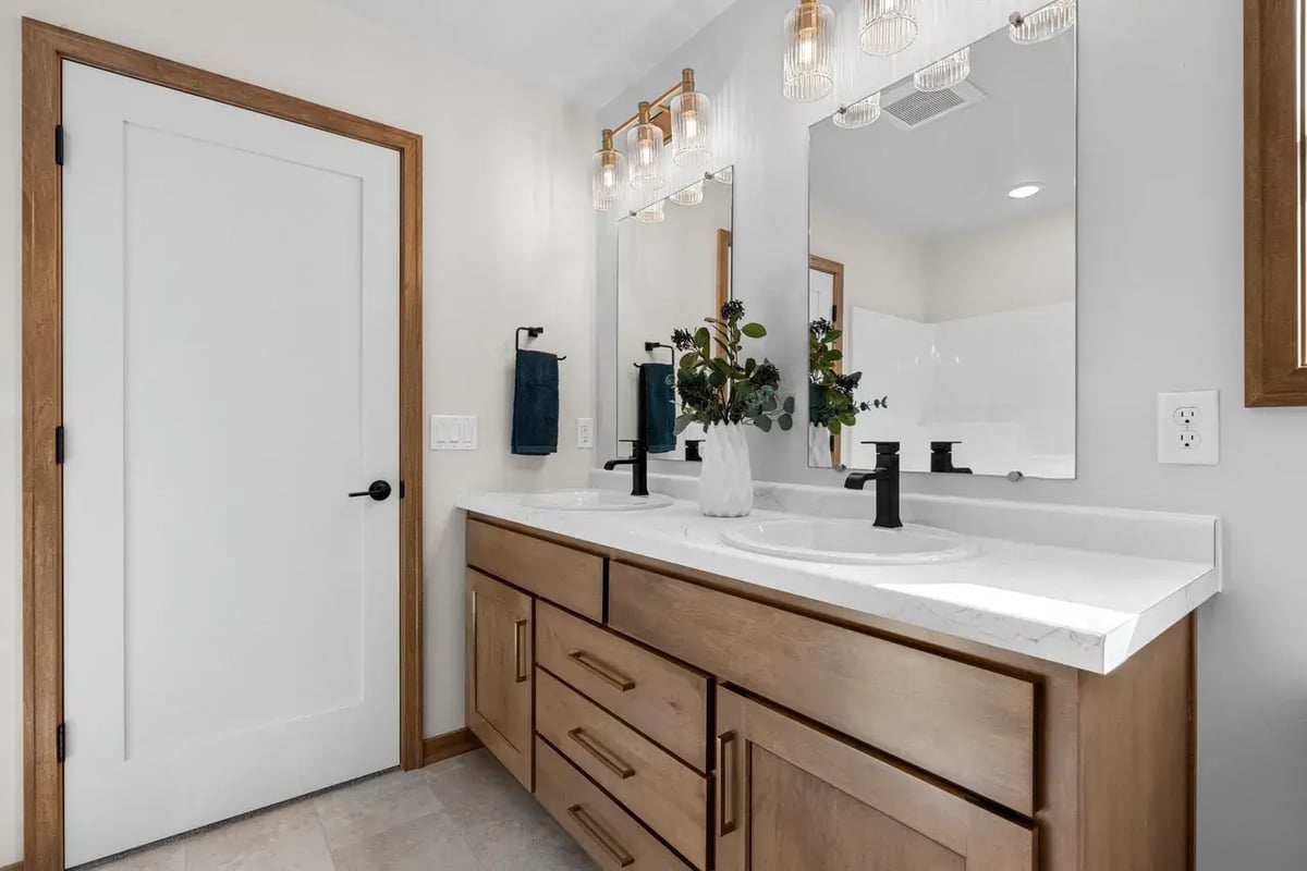 Modern Fox Cities bathroom with double vanity, wood cabinets, matte black faucets, and bright lighting above dual mirrors