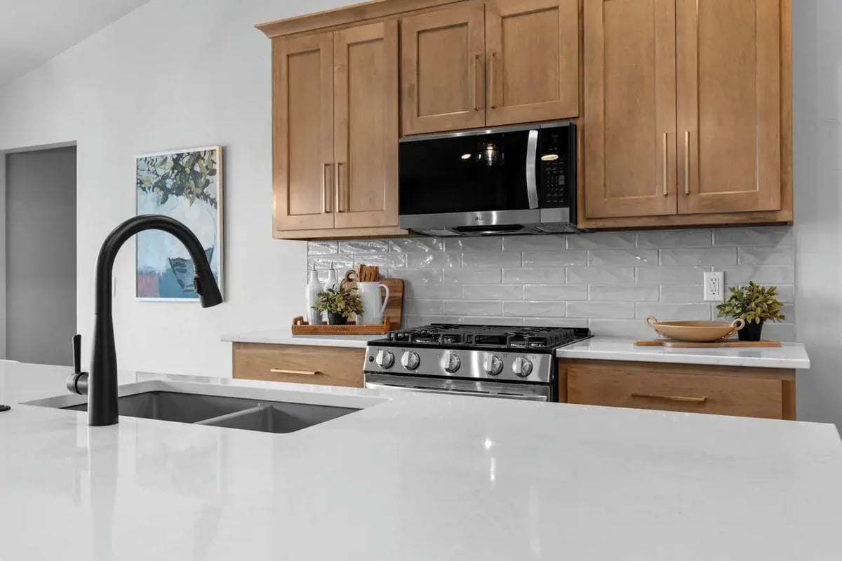 Modern Fox Cities kitchen with island sink, light wood cabinets, white quartz counters, and stainless steel stove and microwave
