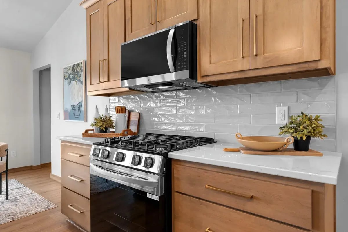 Modern Fox Cities kitchen with stainless steel appliances, light wood cabinets, white tile backsplash, and quartz countertops