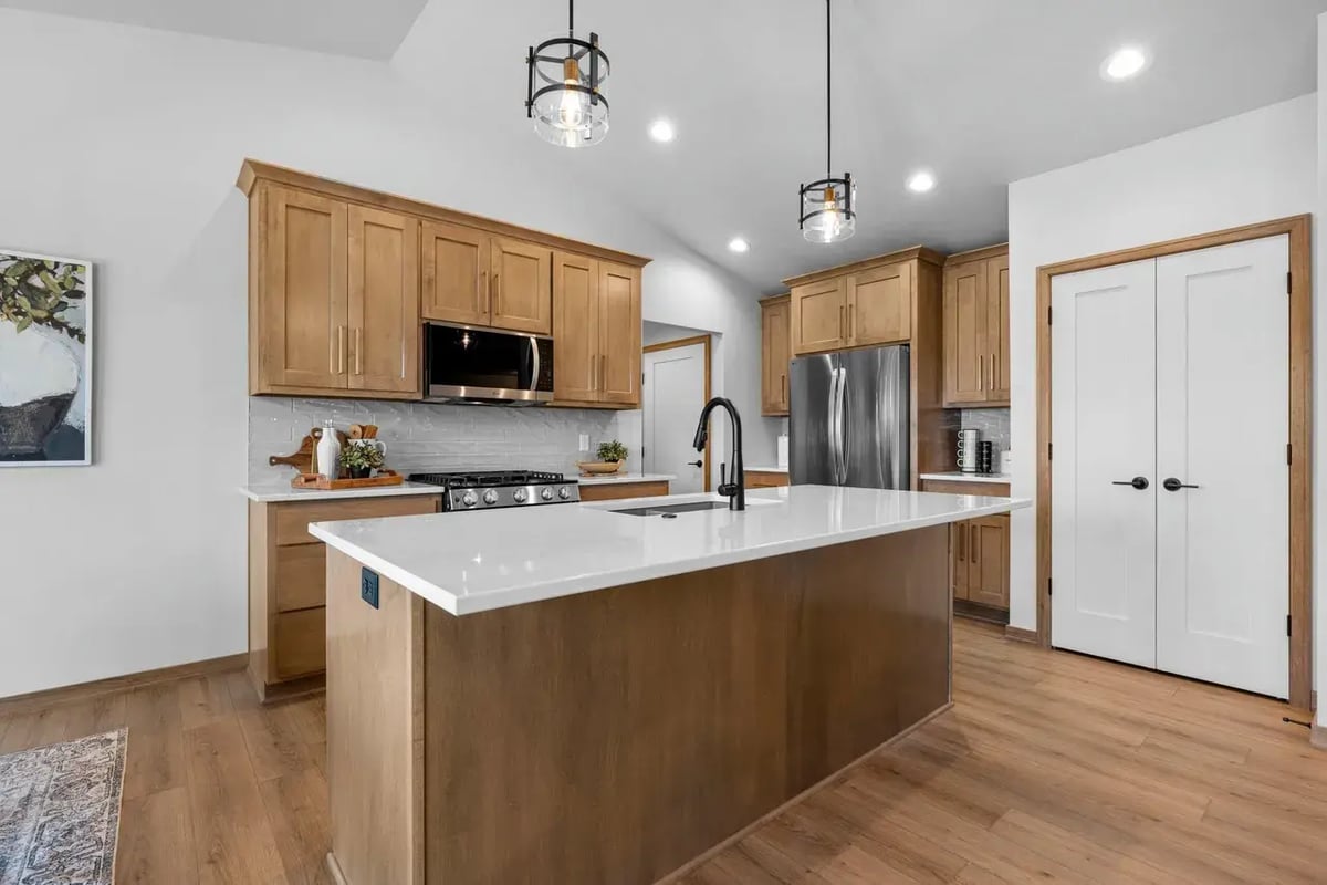 Modern Fox Cities kitchen with wood cabinetry, quartz island, stainless steel appliances, and pendant lighting