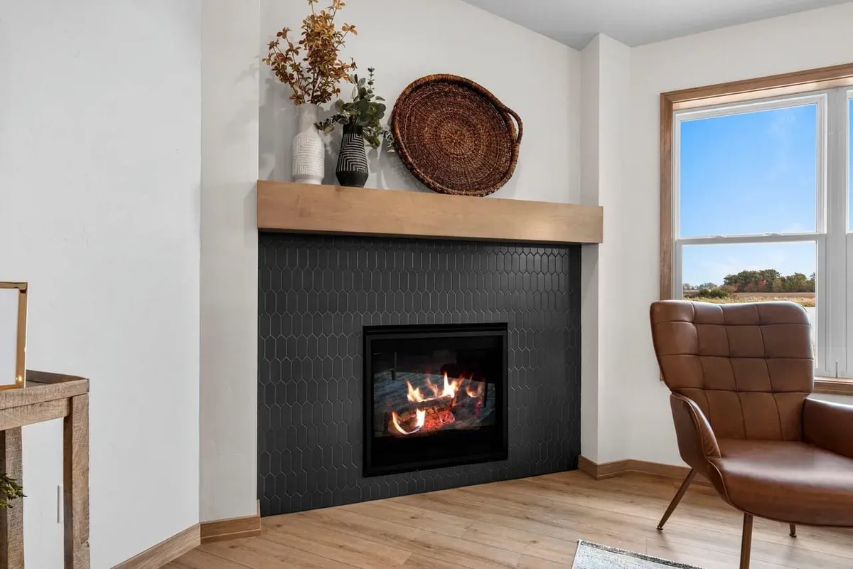 Modern fireplace with black tile surround, wood mantel, and cozy decor located in the Fox Cities