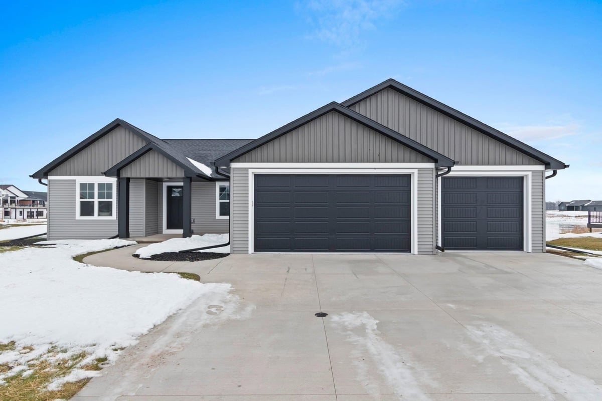 Modern gray ranch home with three-car garage and black trim, located in the snowy Fox Cities neighborhood