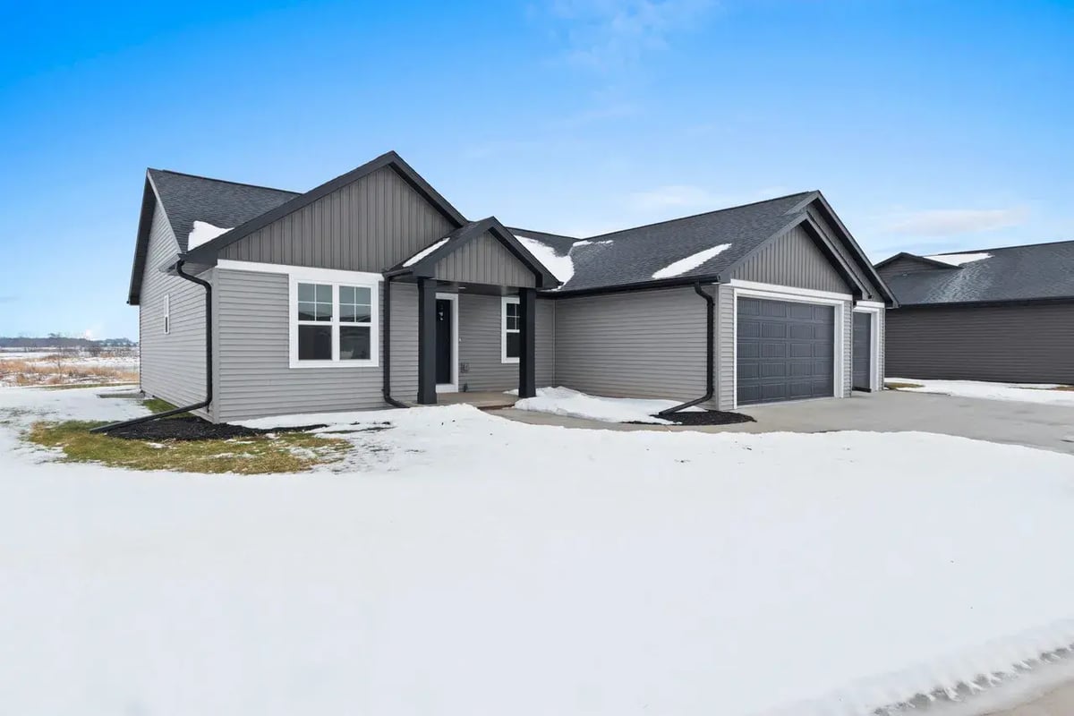 Modern single-story gray home with gable roof and snow-covered yard, located in the Fox Cities
