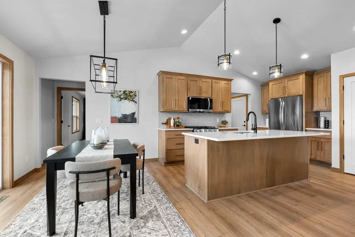 Open-concept Fox Cities kitchen and dining area with wood flooring, island, stainless appliances, and modern light fixtures