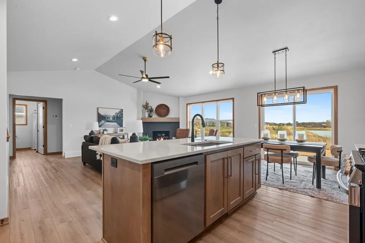 Open-concept kitchen, dining, and living area with modern lighting and scenic views in a Fox Cities home