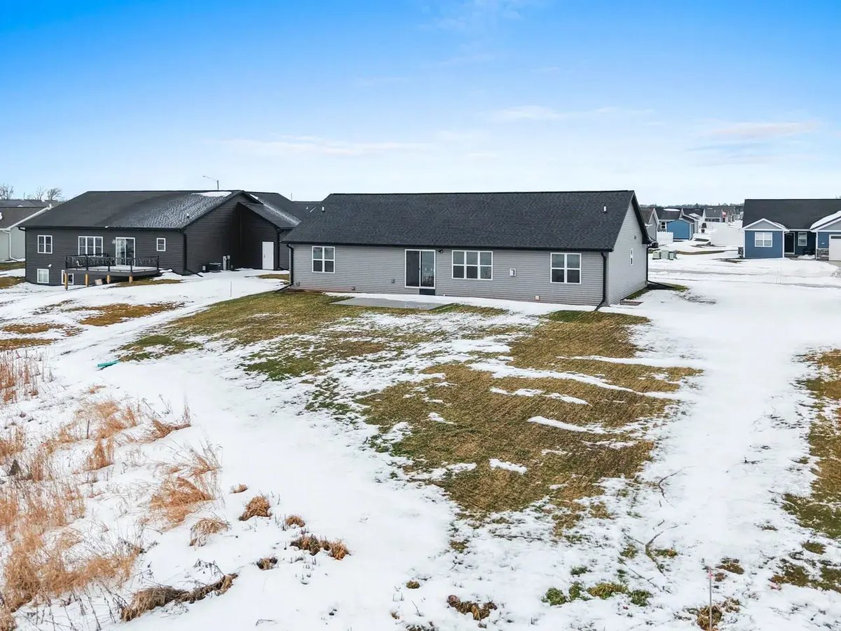 Rear exterior view of a gray ranch-style home with snow-covered lawn and patio, located in the Fox Cities