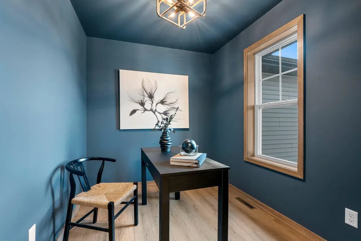 Small blue home office with wood trim, a modern light fixture, and window, located in the Fox Cities