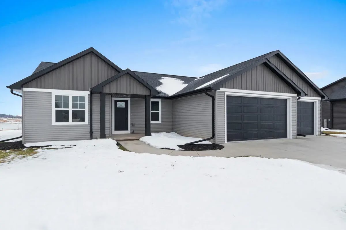 Snow-covered front exterior of a modern gray home with 3-car garage in the Fox Cities