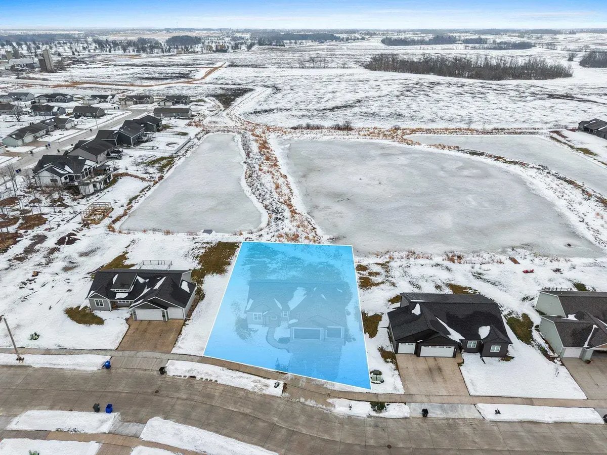 Snow-covered lot outlined in blue located in the Fox Cities, with nearby homes and a frozen pond in a residential neighborhood