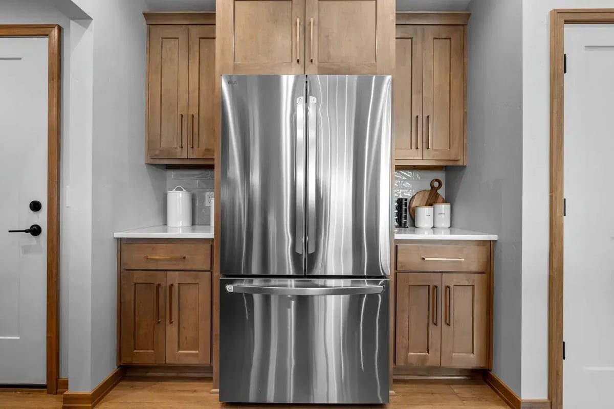 Stainless steel fridge with wood cabinetry and white countertops in a Fox Cities kitchen